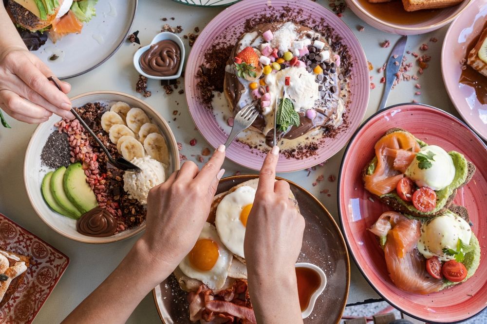 breakfast spread on a table with people digging in